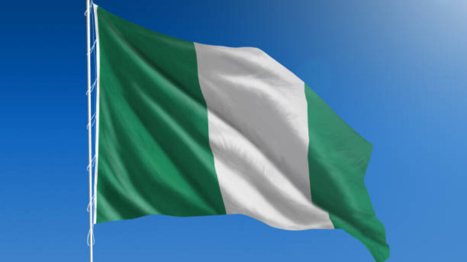 The National flag of Nigeria blowing in the wind in front of a clear blue sky